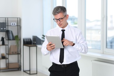 Photo of Businessman with glasses using tablet in office