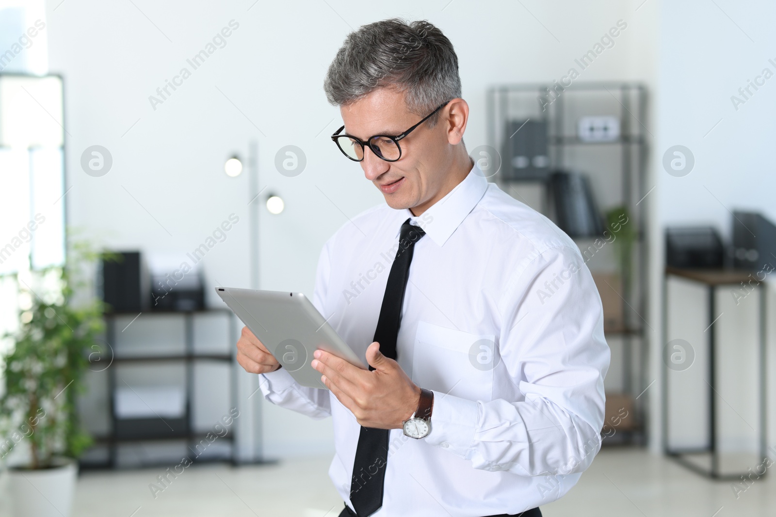 Photo of Businessman with glasses using tablet in office