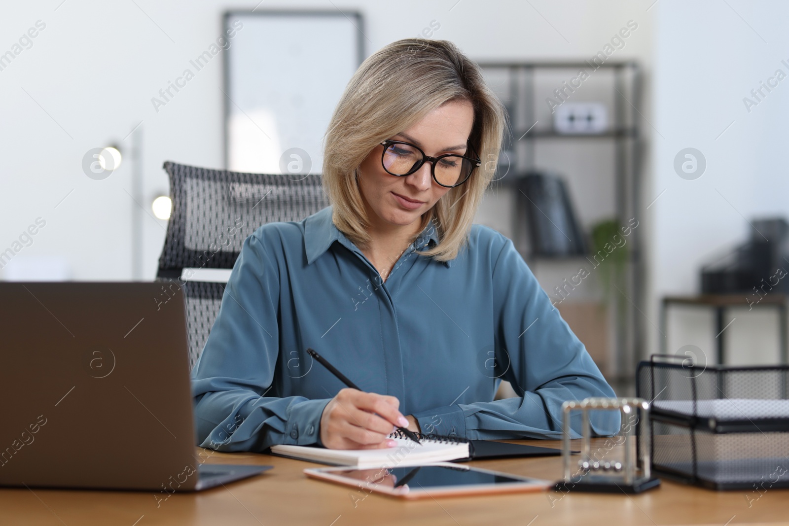 Photo of Businesswoman taking notes at table in office