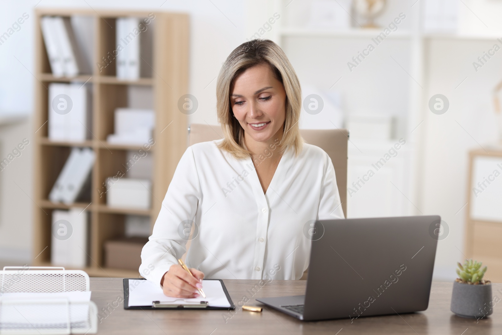 Photo of Businesswoman taking notes at table in office