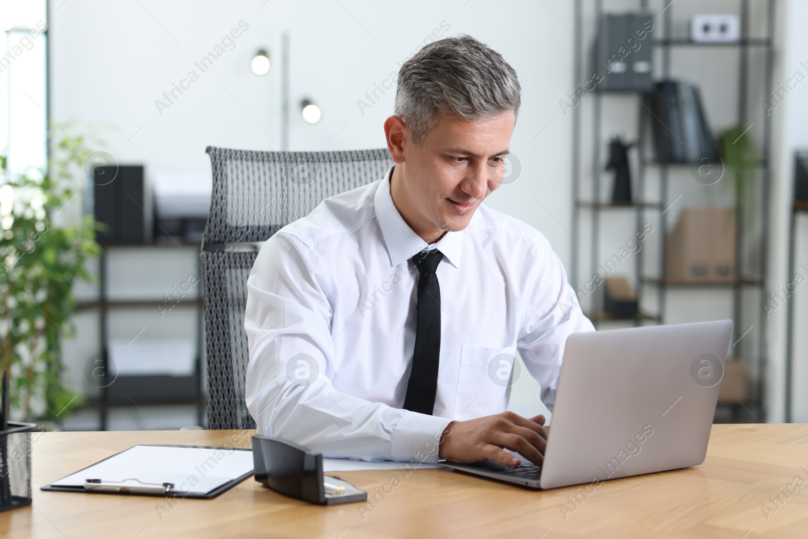 Photo of Businessman working on laptop at table in office