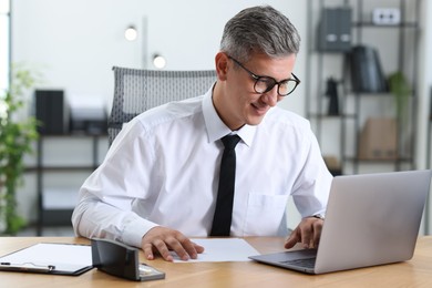 Photo of Businessman working on laptop at table in office