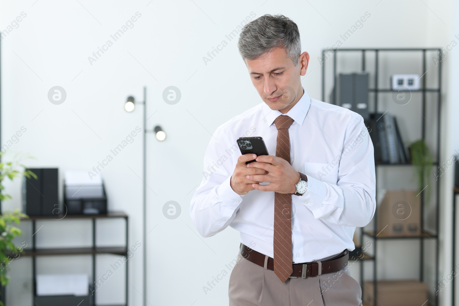 Photo of Portrait of businessman using smartphone in office, space for text