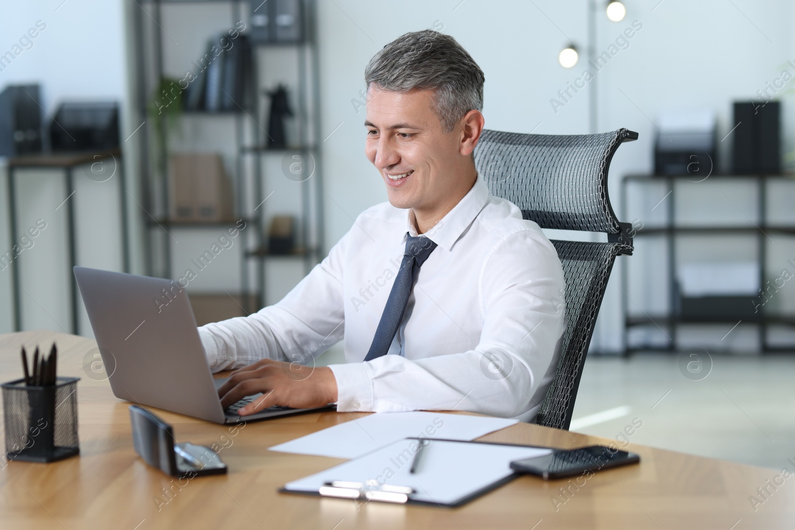 Photo of Businessman working on laptop at table in office