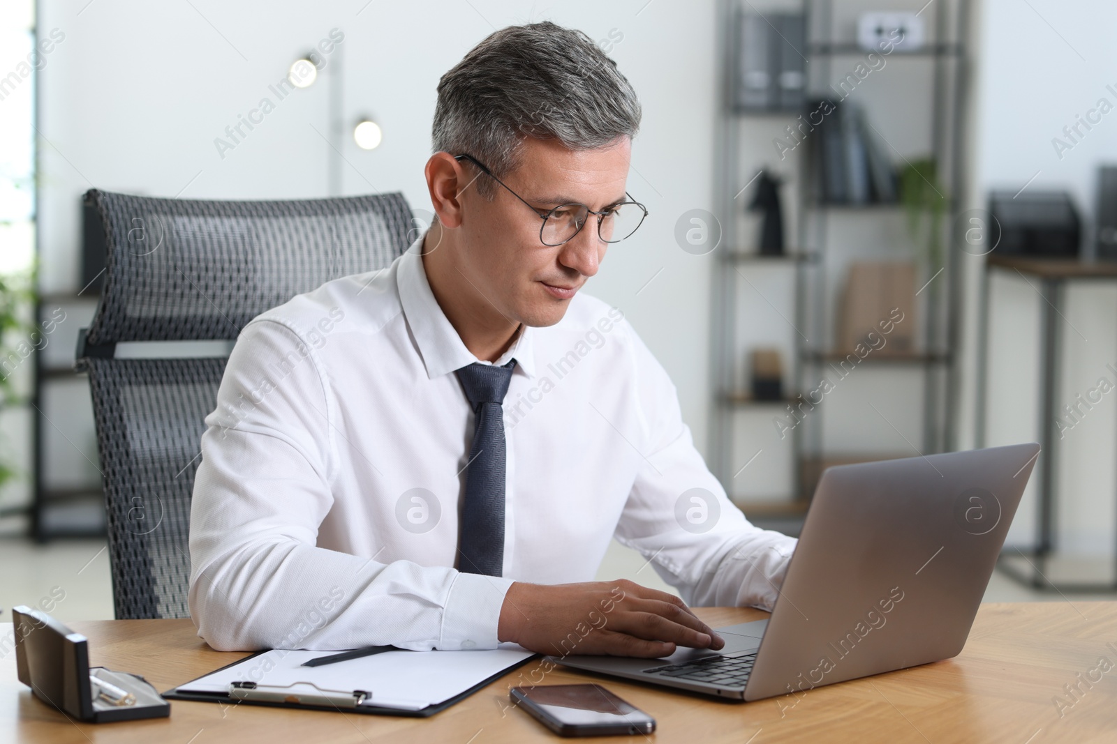 Photo of Businessman working on laptop at table in office