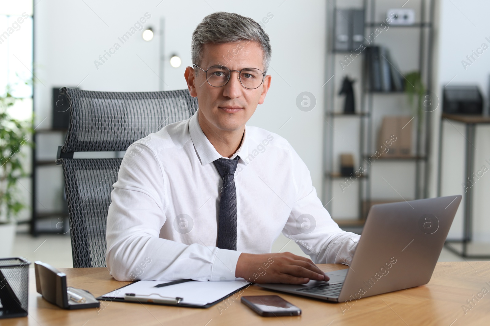 Photo of Businessman working on laptop at table in office