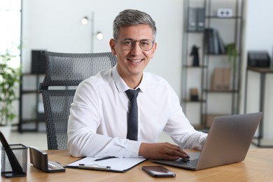 Photo of Businessman working on laptop at table in office