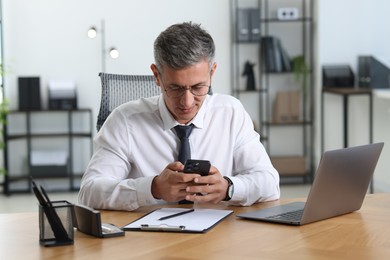 Photo of Businessman using smartphone at table in office