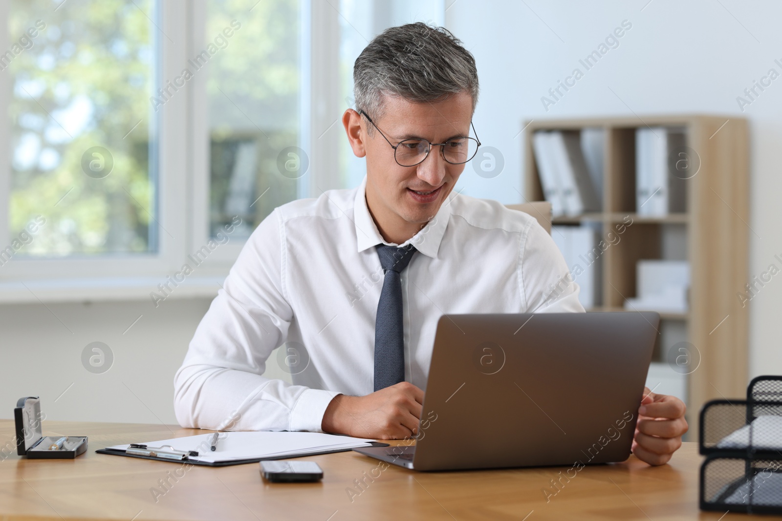 Photo of Businessman working on laptop at table in office