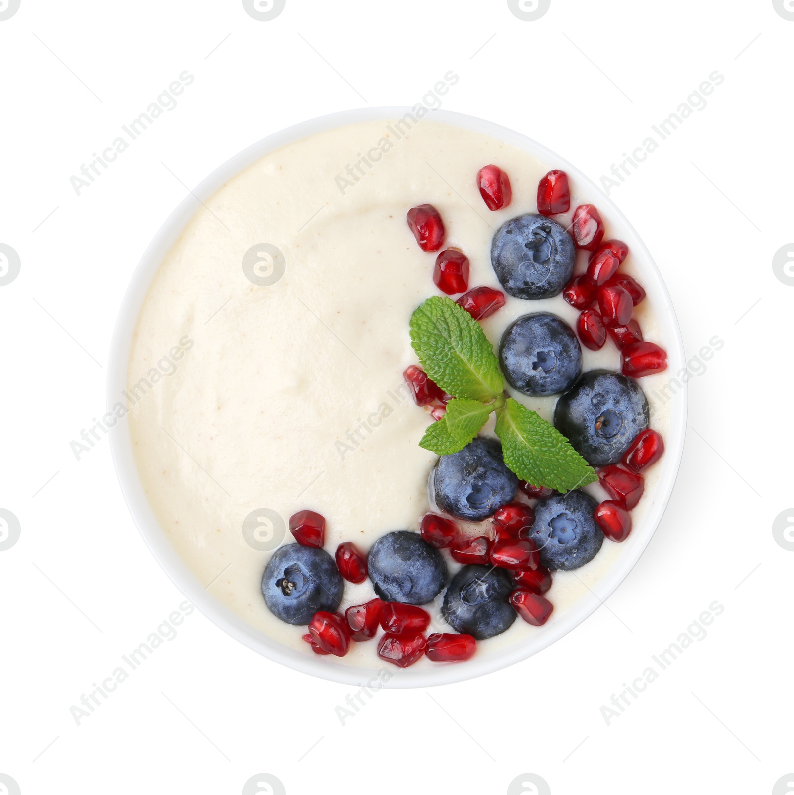 Photo of Tasty cooked semolina porridge with blueberries, pomegranate and mint isolated on white, top view