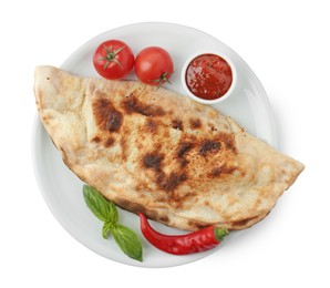 Photo of Delicious calzone with ketchup, fresh tomatoes and chili pepper isolated on white, top view