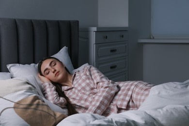 Photo of Young woman sleeping in soft bed at night