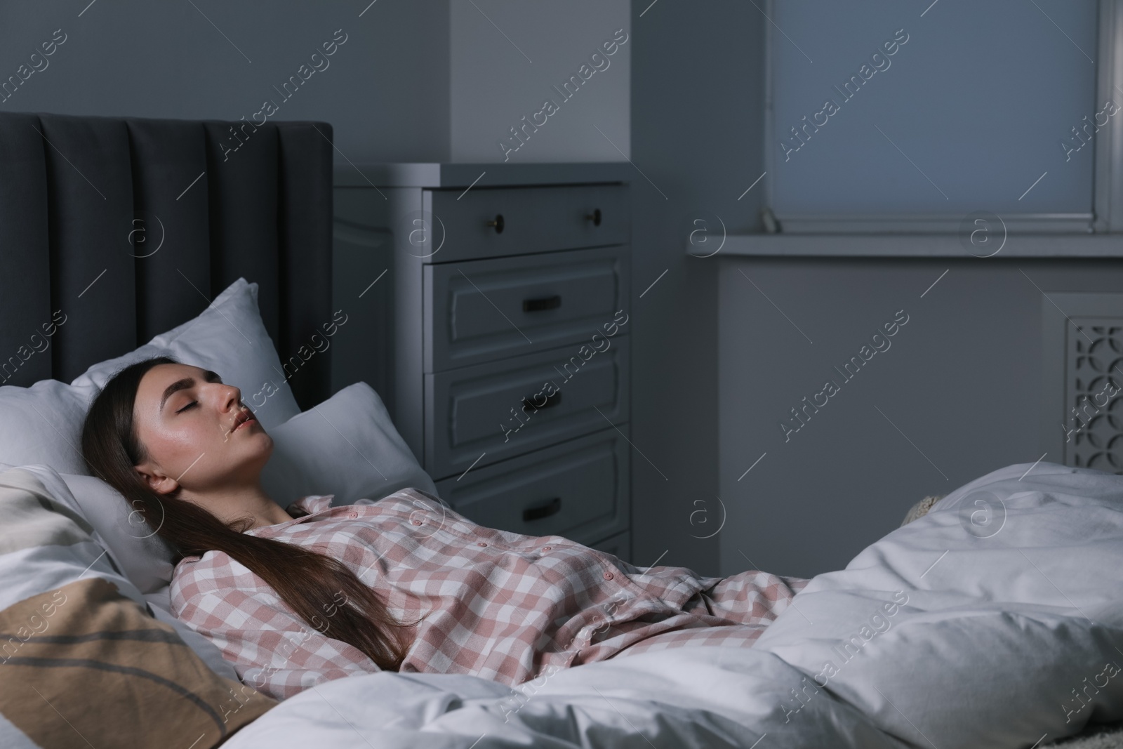 Photo of Young woman sleeping in soft bed at night