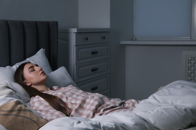 Photo of Young woman sleeping in soft bed at night