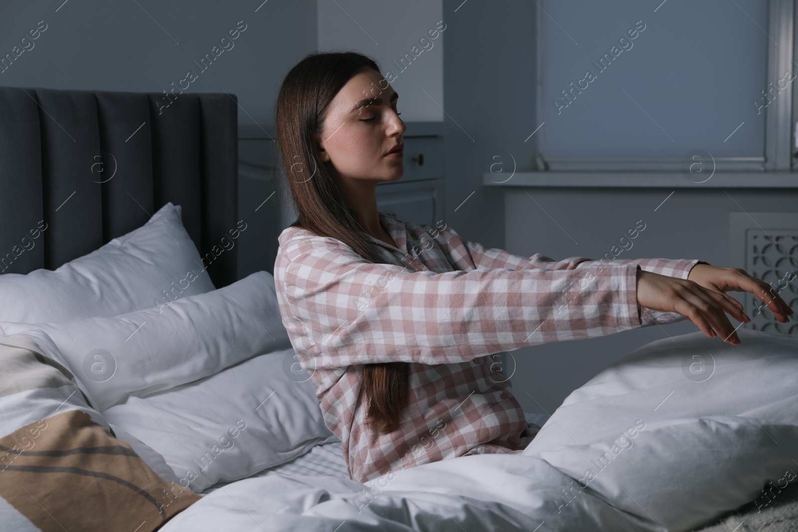 Photo of Young woman suffering from sleepwalking on bed at home