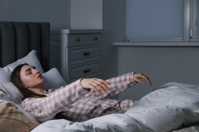 Photo of Young woman suffering from sleepwalking on bed at home