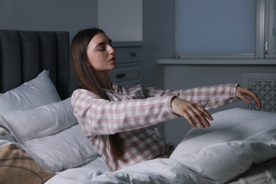 Photo of Young woman suffering from sleepwalking on bed at home