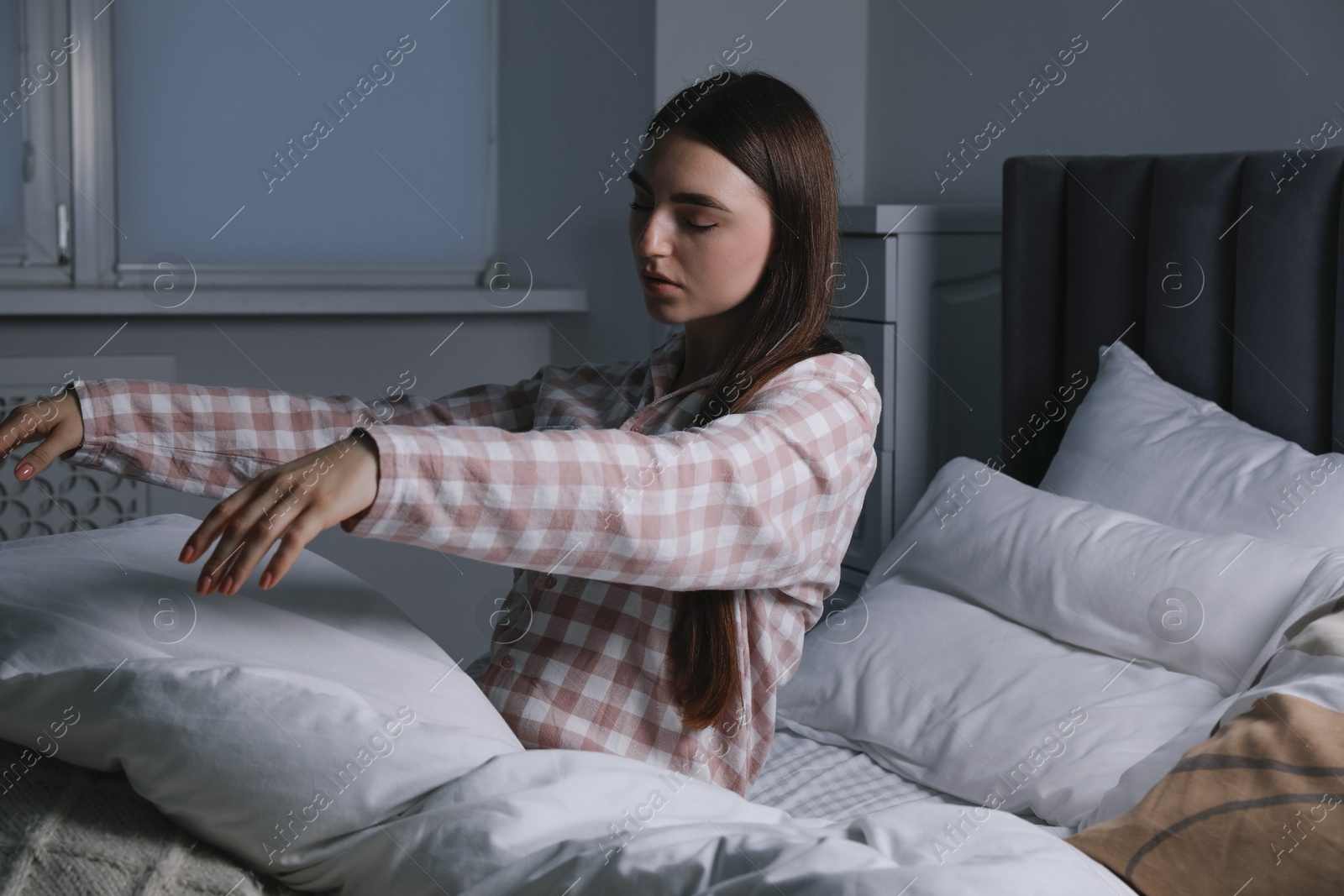 Photo of Young woman suffering from sleepwalking on bed at home