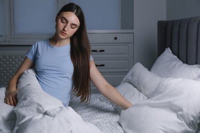 Photo of Young woman suffering from sleepwalking on bed at home