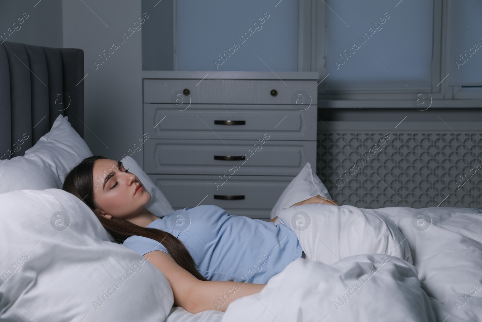 Photo of Young woman sleeping in soft bed at night