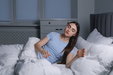 Photo of Young woman suffering from sleepwalking on bed at home