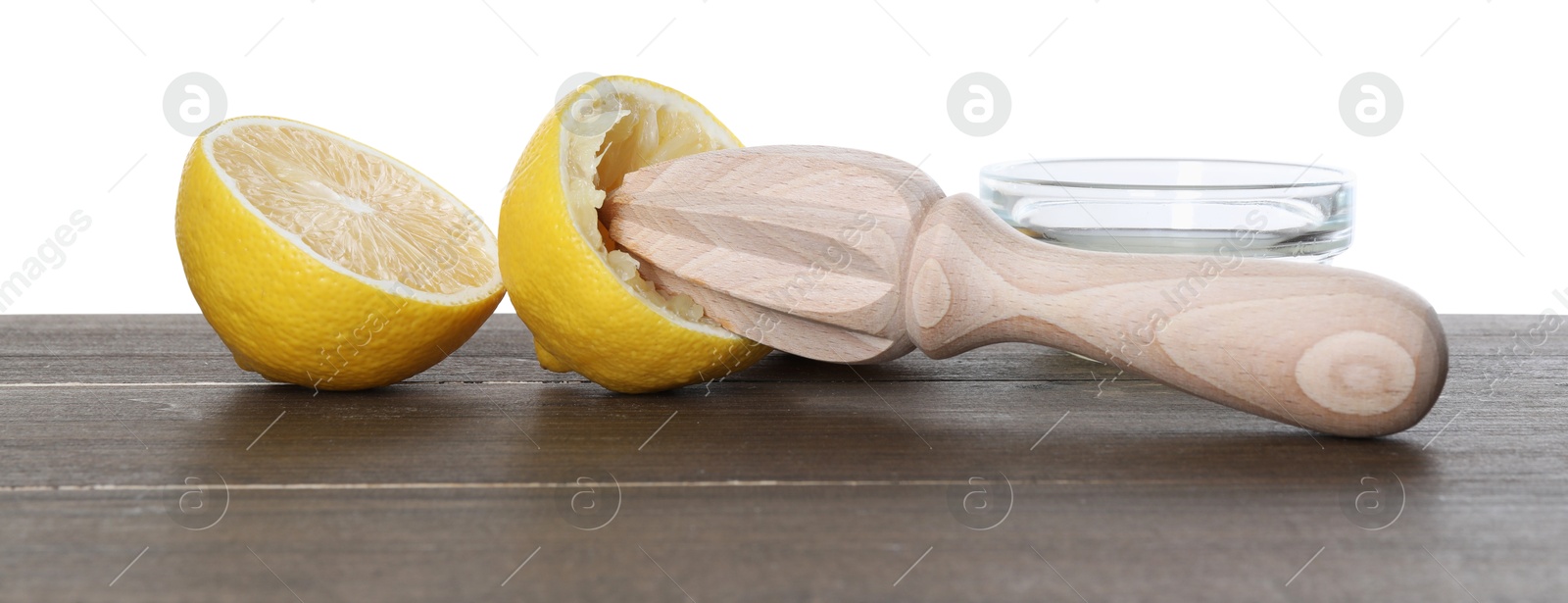 Photo of Juicer and fresh lemons on wooden table against white background