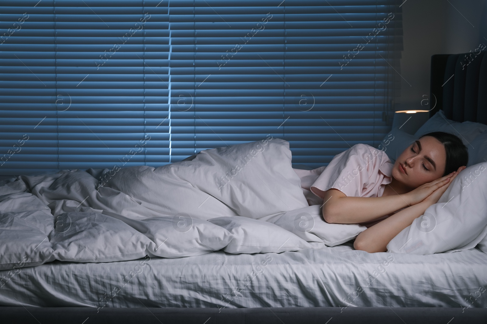 Photo of Young woman sleeping in soft bed at night