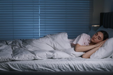 Photo of Young woman sleeping in soft bed at night