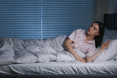 Photo of Young woman suffering from sleepwalking on bed at home