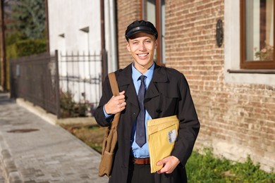 Photo of Happy postman with parcels outdoors. Mail service