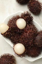 Delicious ripe rambutans on light grey table, top view