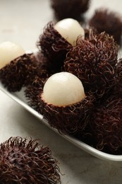 Photo of Delicious ripe rambutans on light grey table, closeup