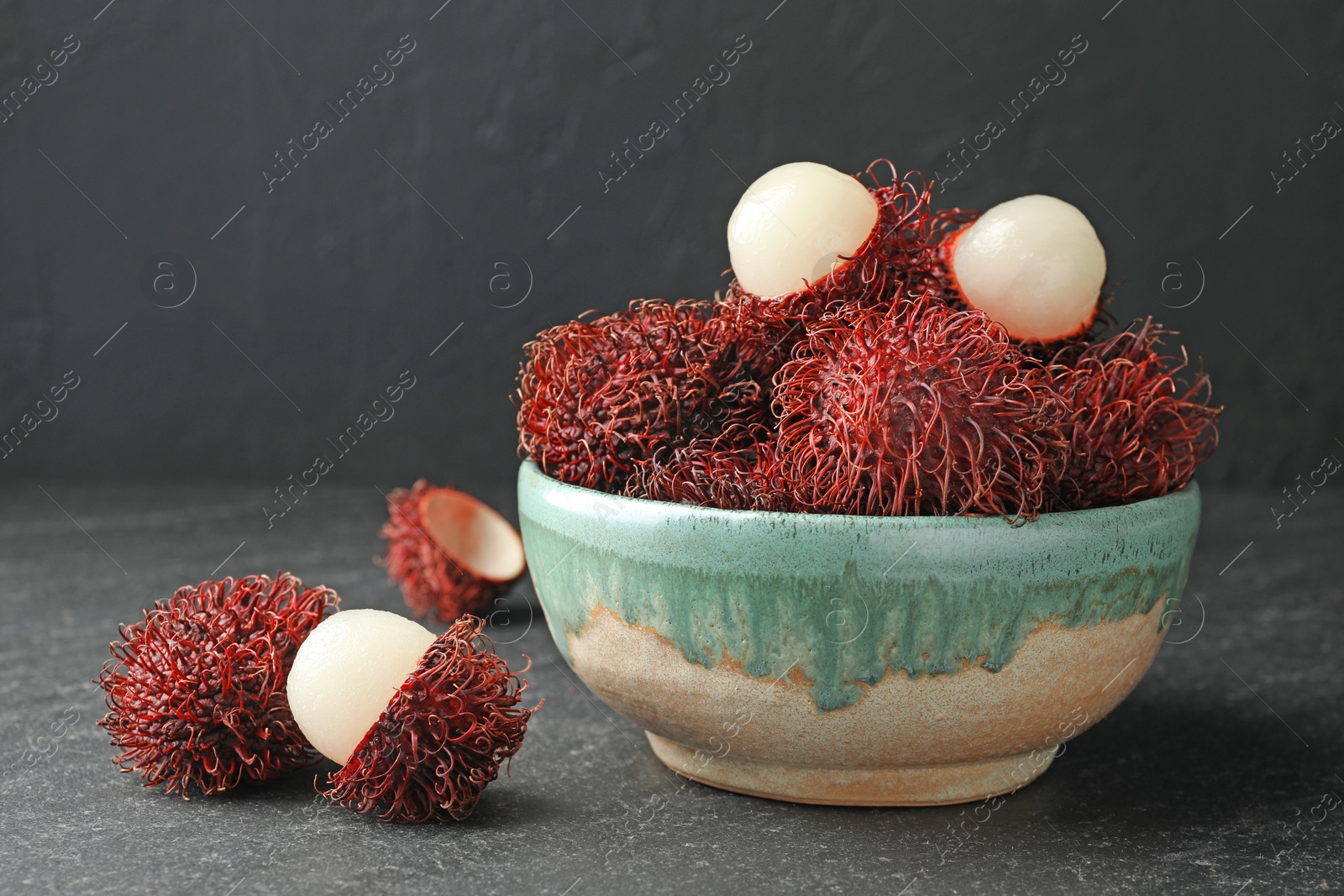 Photo of Delicious ripe rambutans in bowl on black table