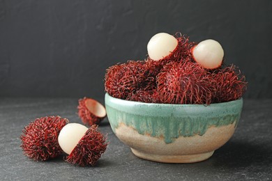 Photo of Delicious ripe rambutans in bowl on black table