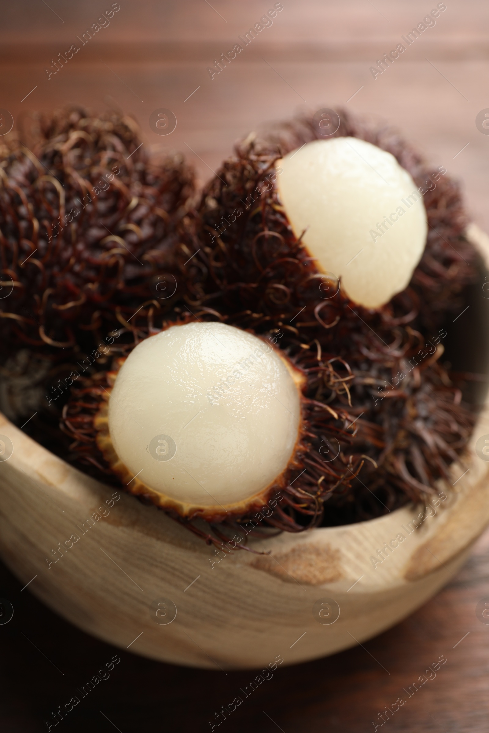 Photo of Delicious ripe rambutans in bowl on table, closeup