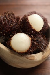 Photo of Delicious ripe rambutans in bowl on table, closeup