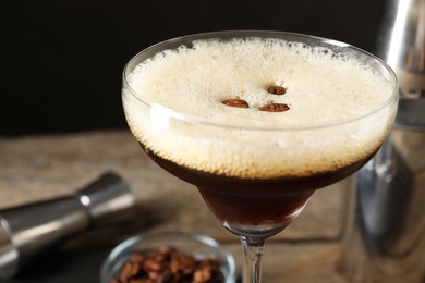 Photo of Delicious espresso martini with coffee beans in glass on blurred background, closeup