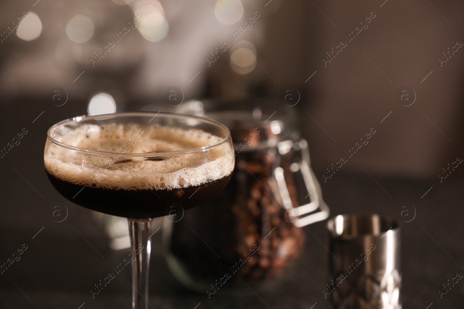 Photo of Delicious espresso martini in glass on blurred background, closeup. Space for text