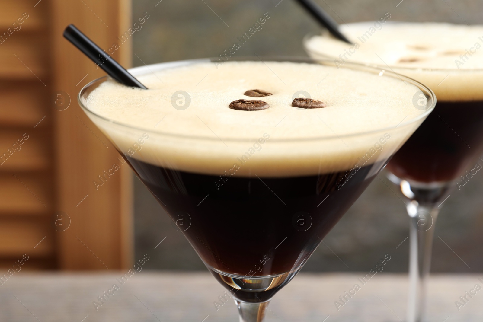 Photo of Glasses of delicious espresso martini with coffee beans on table, closeup