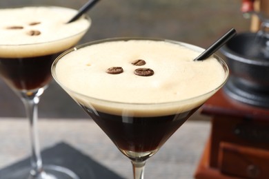 Photo of Glasses of delicious espresso martini with coffee beans on table, closeup