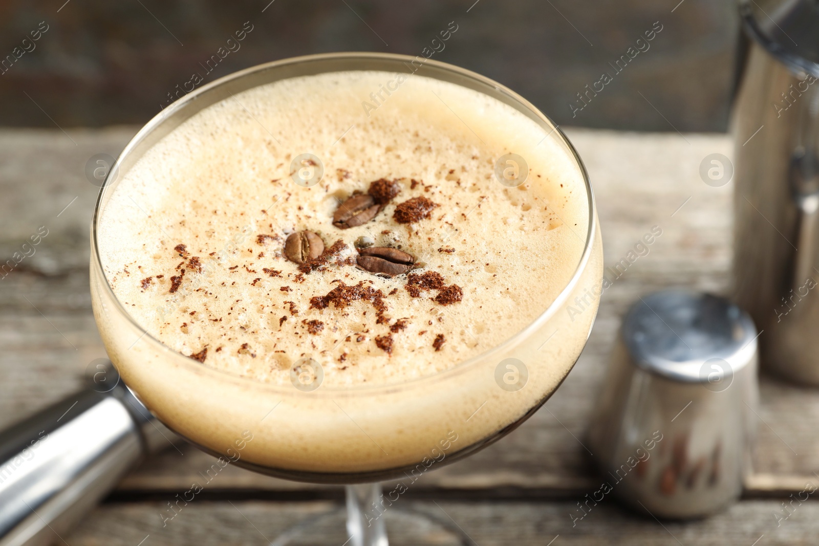 Photo of Delicious espresso martini with coffee beans in glass on table, closeup