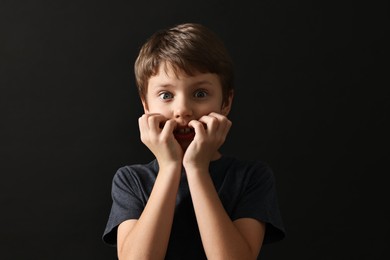 Photo of Portrait of scared little boy on black background