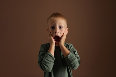 Photo of Scared little boy screaming on brown background