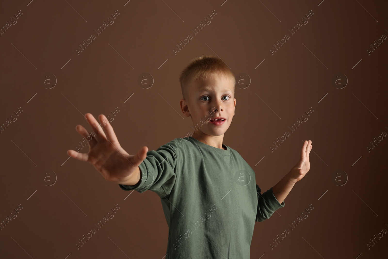 Photo of Portrait of scared little boy on brown background