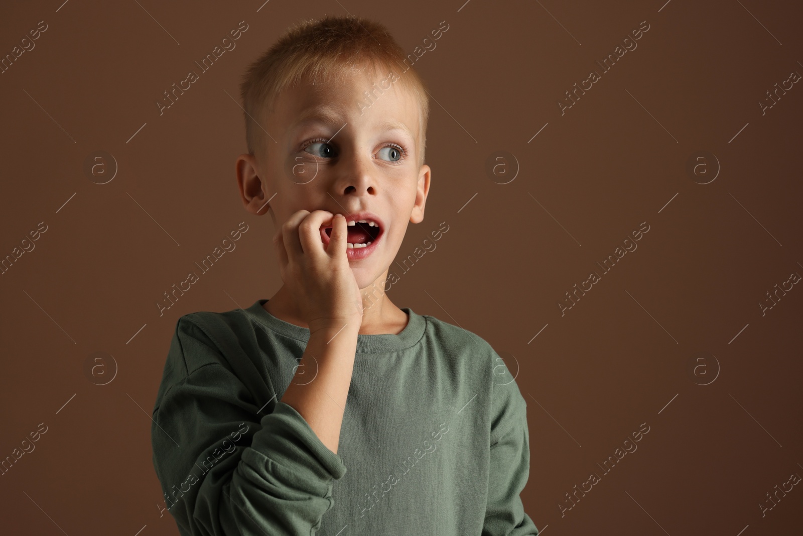 Photo of Scared little boy on brown background. Space for text