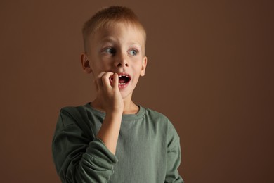 Scared little boy on brown background. Space for text