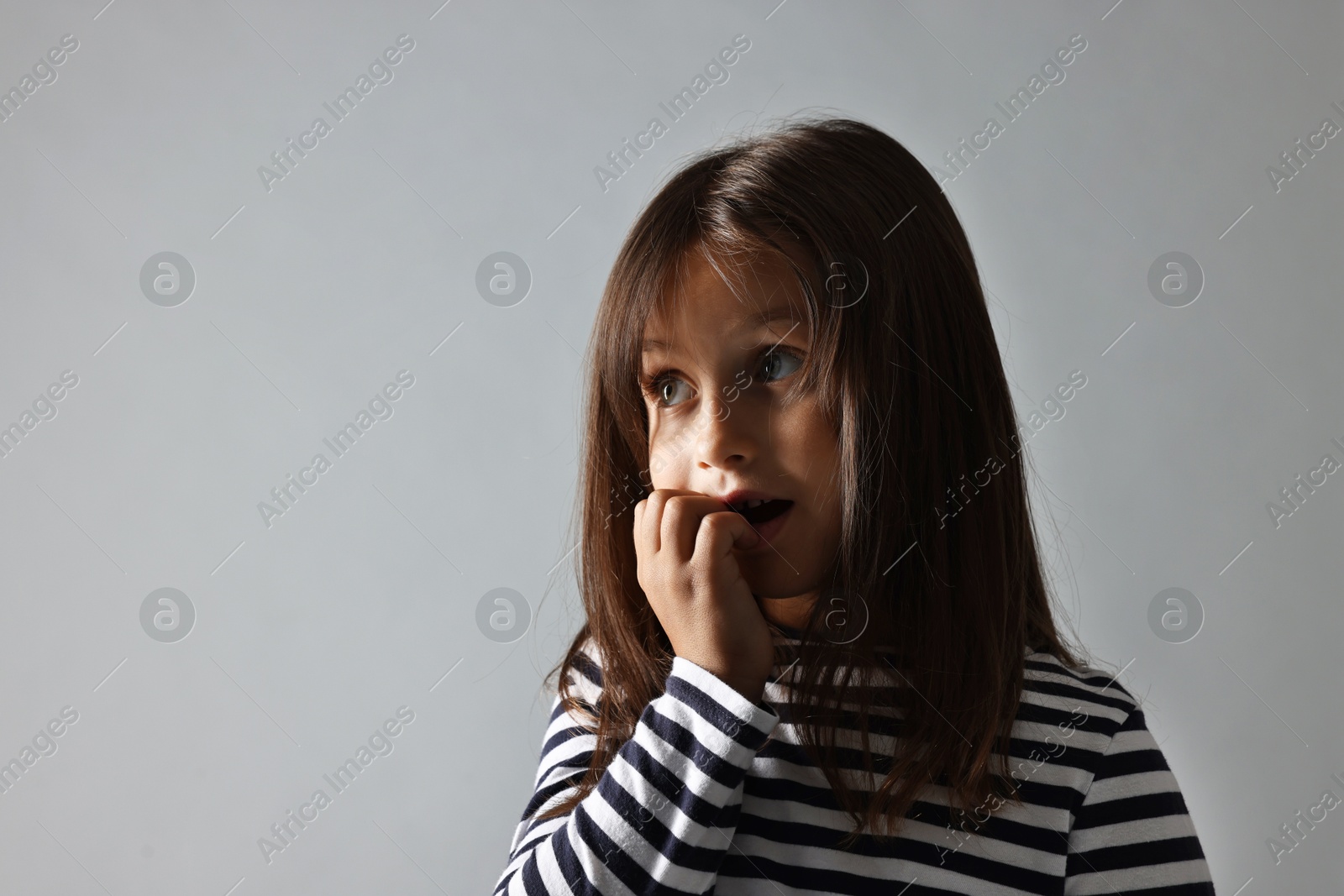 Photo of Scared little girl on grey background. Space for text