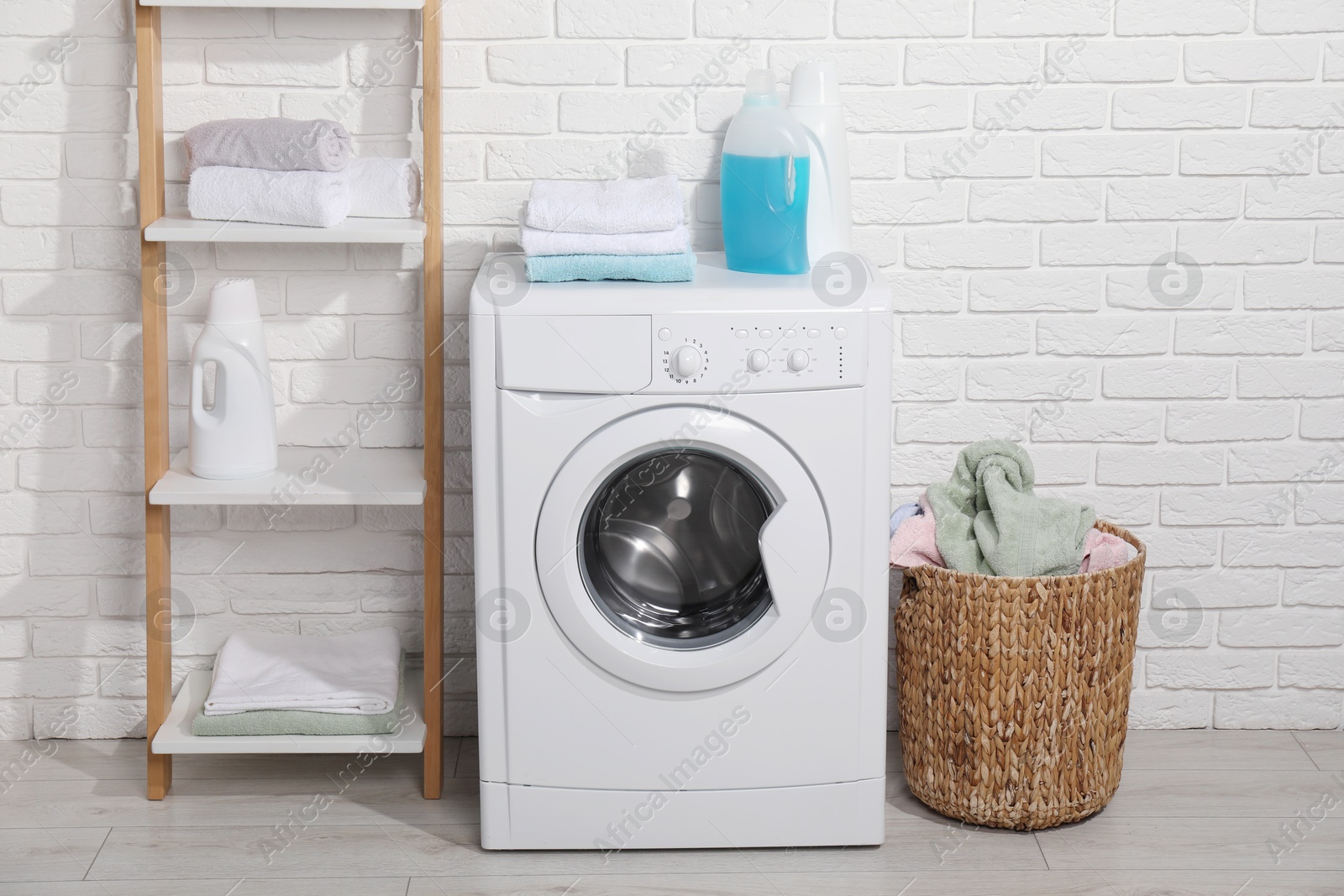 Photo of Laundry detergents and stacked clean towels on washing machine in bathroom