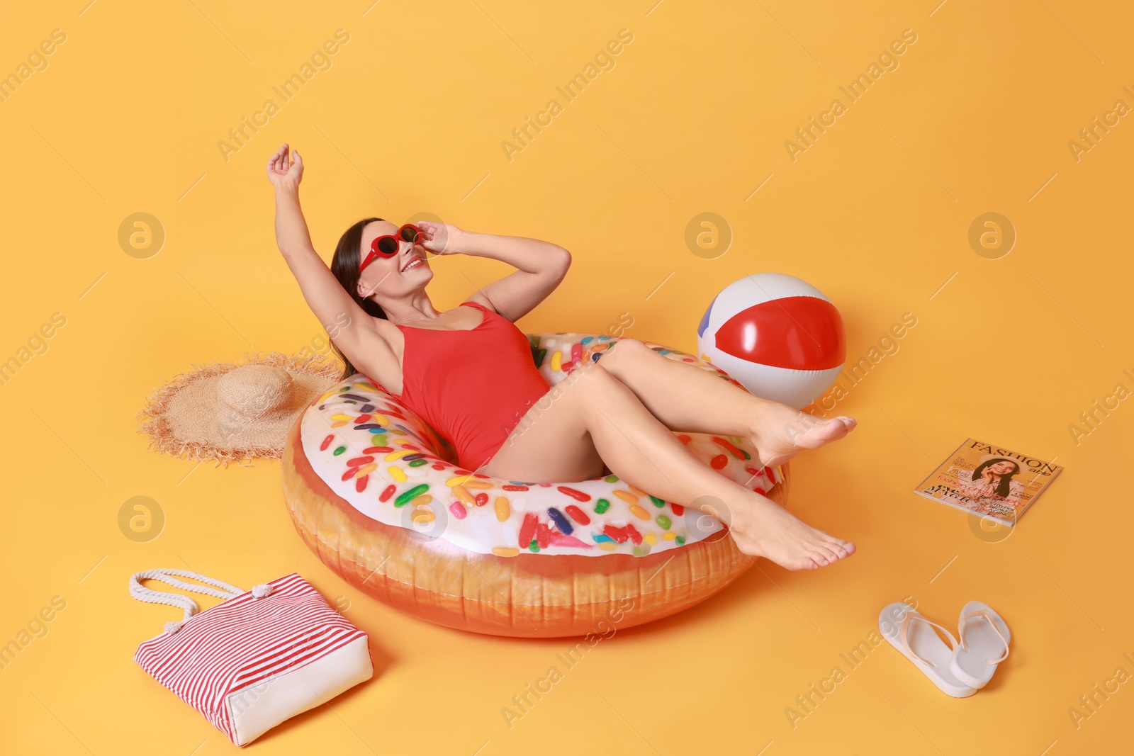 Photo of Beautiful woman in swimsuit with beach accessories on yellow background