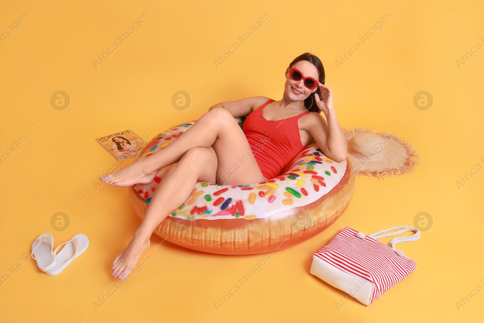 Photo of Beautiful woman in swimsuit with beach accessories on yellow background